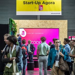 groupe de personne réunit au salon professionel Paris Retail Week et devant une bannière avec écrit start-up